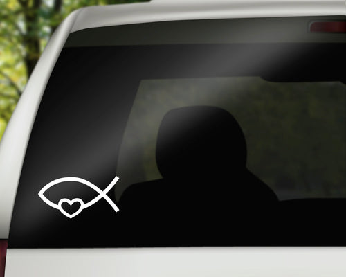Close-up digital mockup of a white Christian fish and heart vinyl decal on a car window